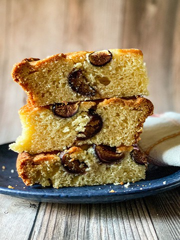 Skillet fig cake in slices stacked on top of each other on a black plate.