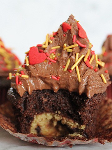 Stuffed cookie dough cupcake with chocolate frosting and Valentine's Day decorations.