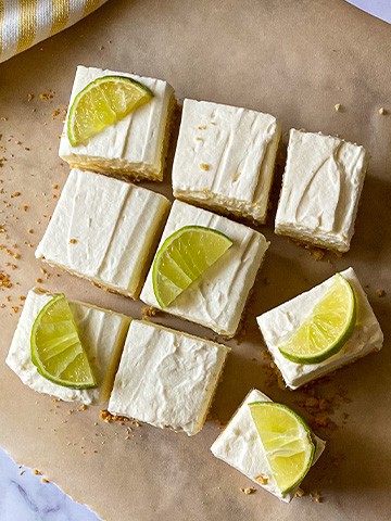 Key lime pie bars slices with limes on top.