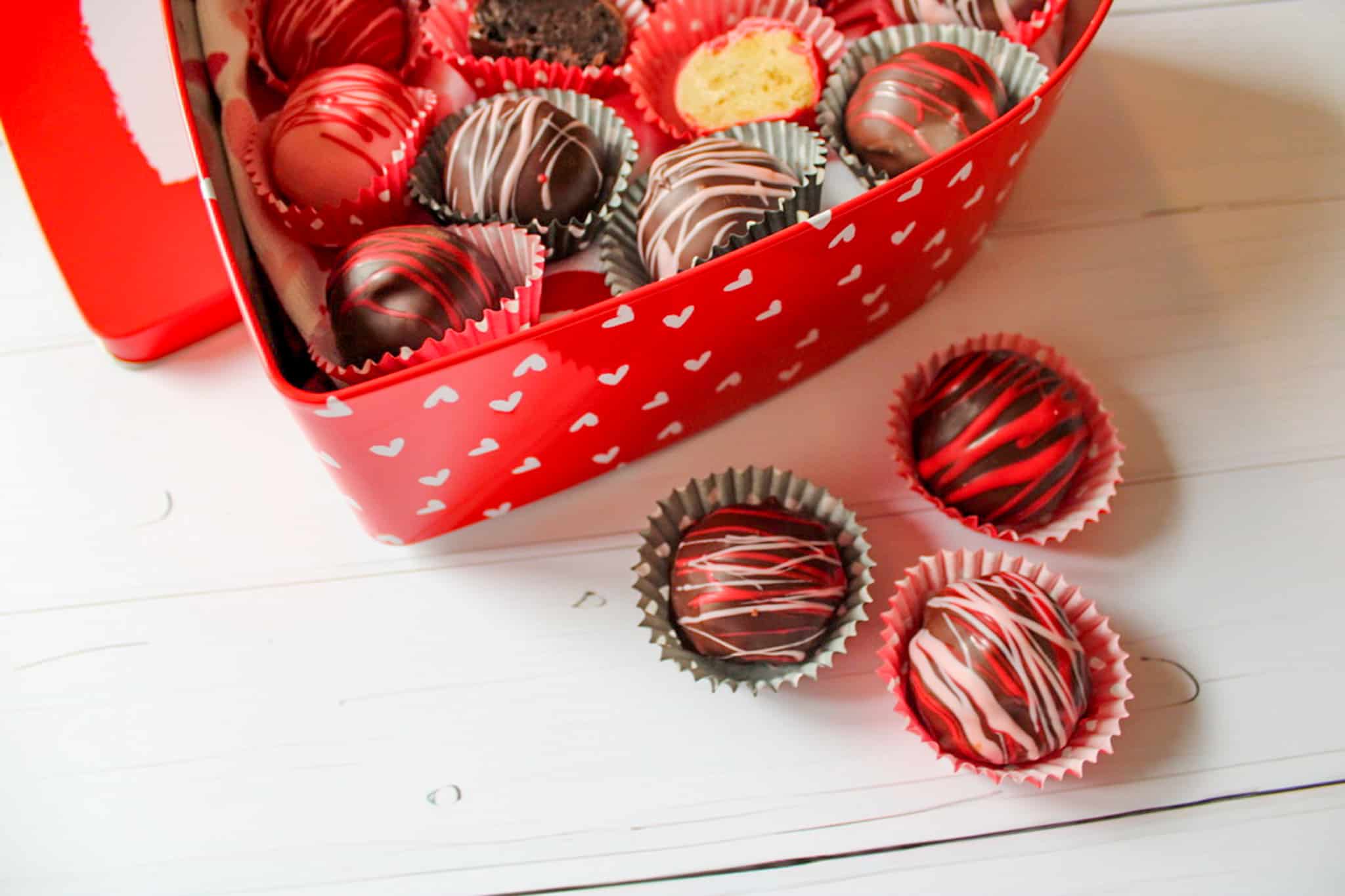 Oreo truffles in a box with three outside of the box on the table. 