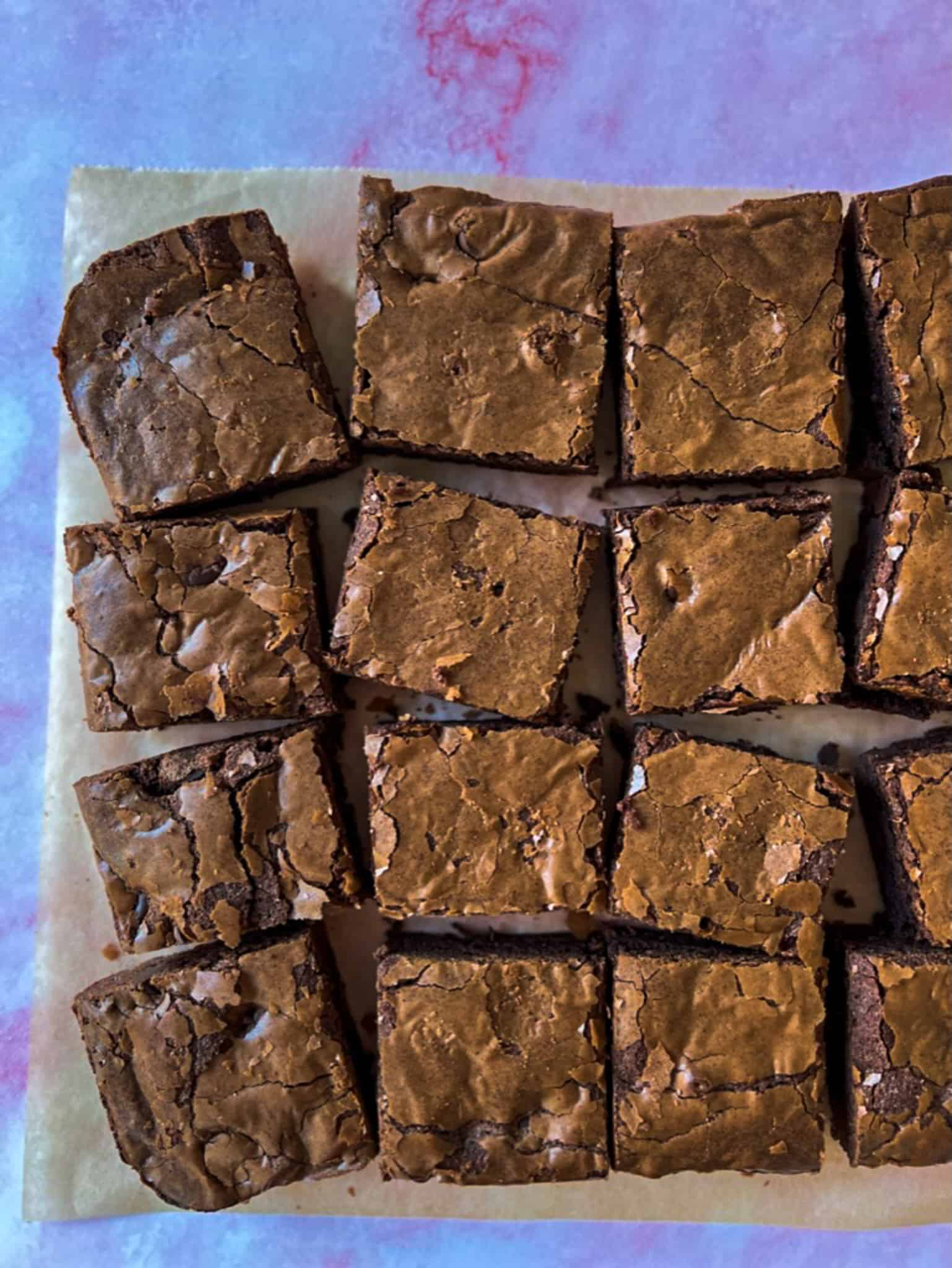 Brown butter brownies cut up and spread out on a sheet of parchment. 