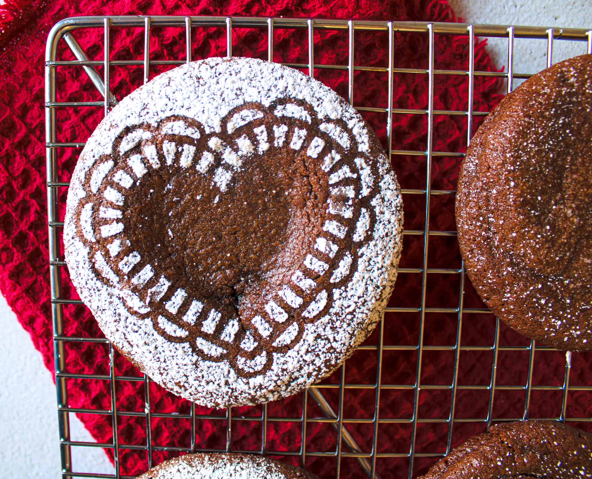 A lava cake cookie with a powdered sugar heat resting on a cooling rack. 