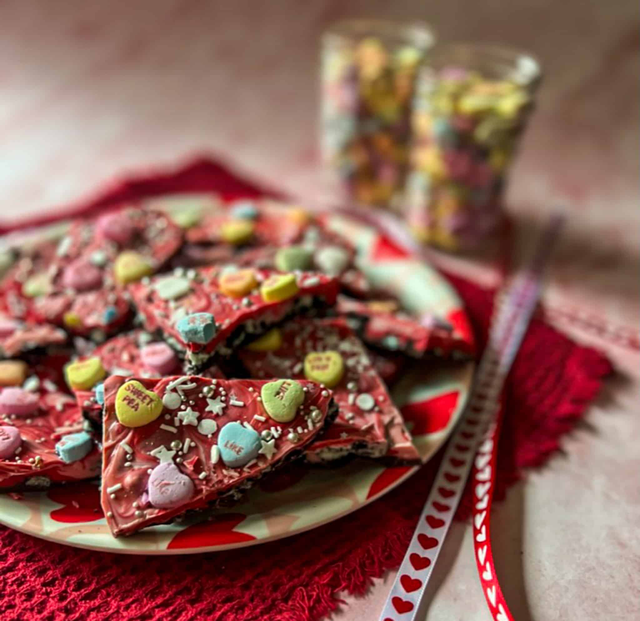 Valentine's Day chocolate bark on a heart-themed plate with candy heart decorations. 