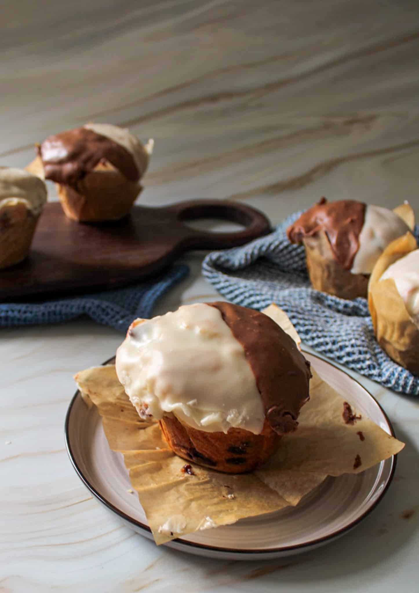 A black and white muffin on a plate with more black and white muffins in the background. 