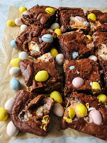 Cut up Easter brownies surrounded by chocolate eggs.