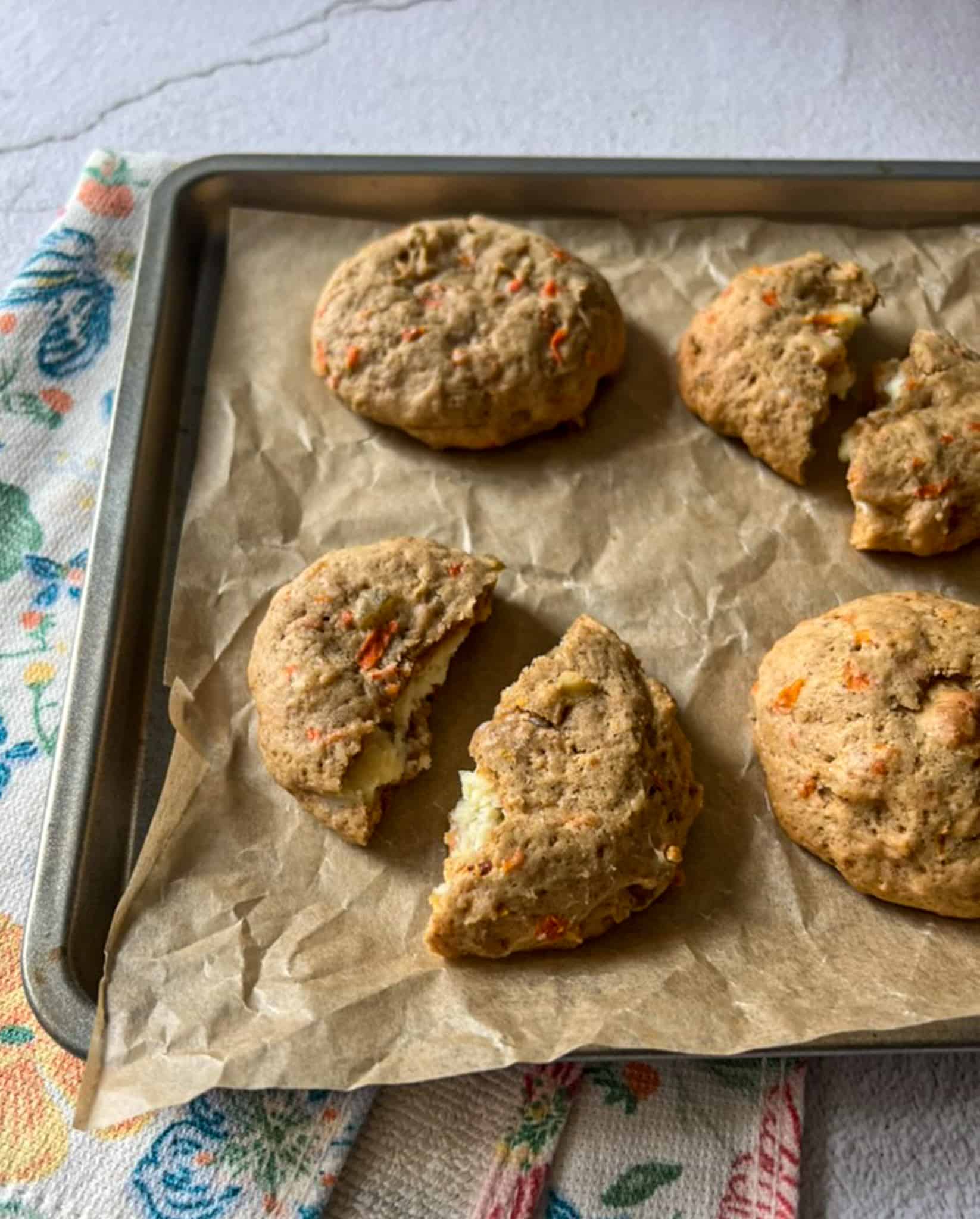 Stuffed carrot cake cookies on a cookie sheet with some split open. 