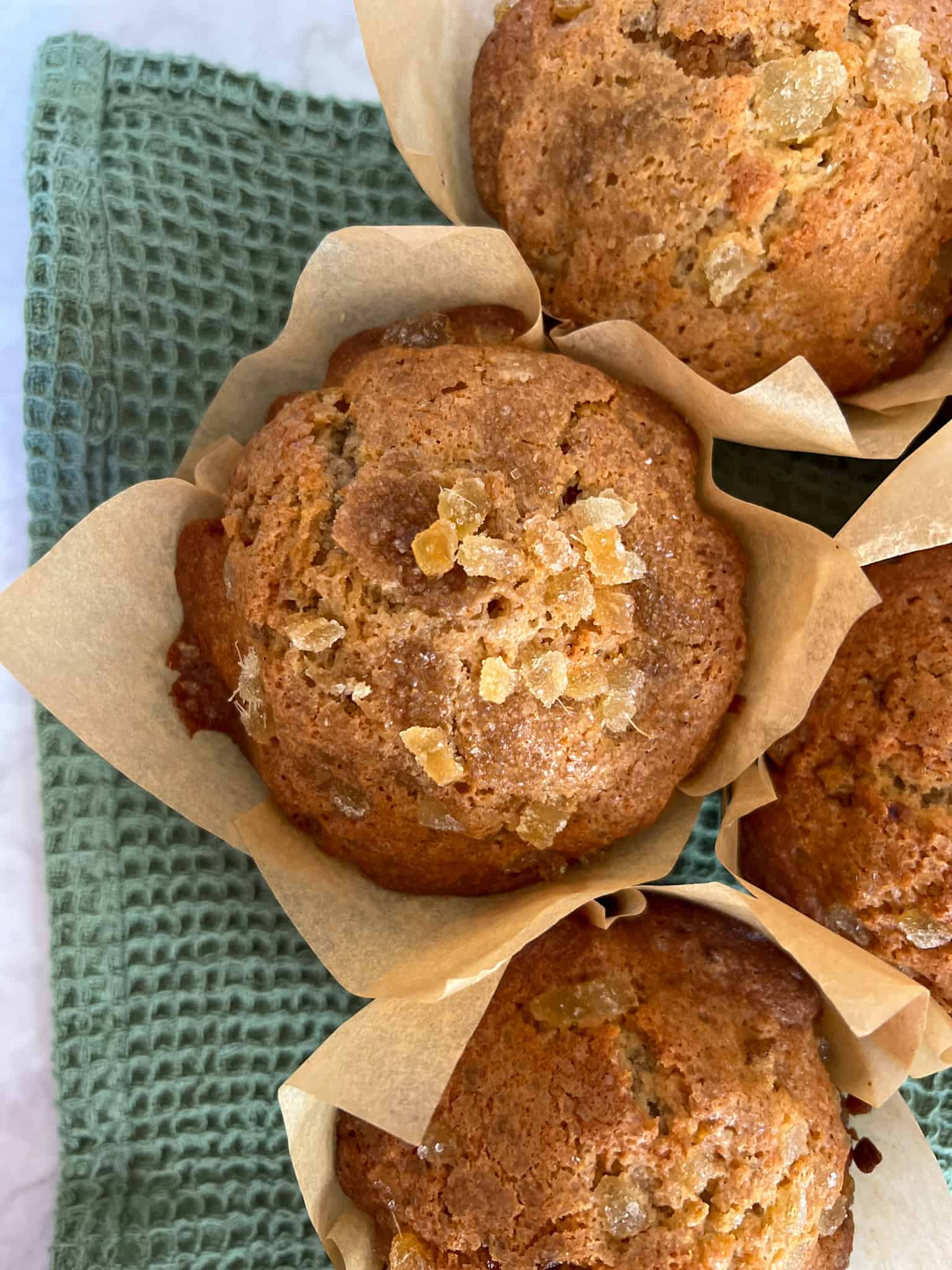 Buckwheat ginger muffins sitting on top of a green tea towel