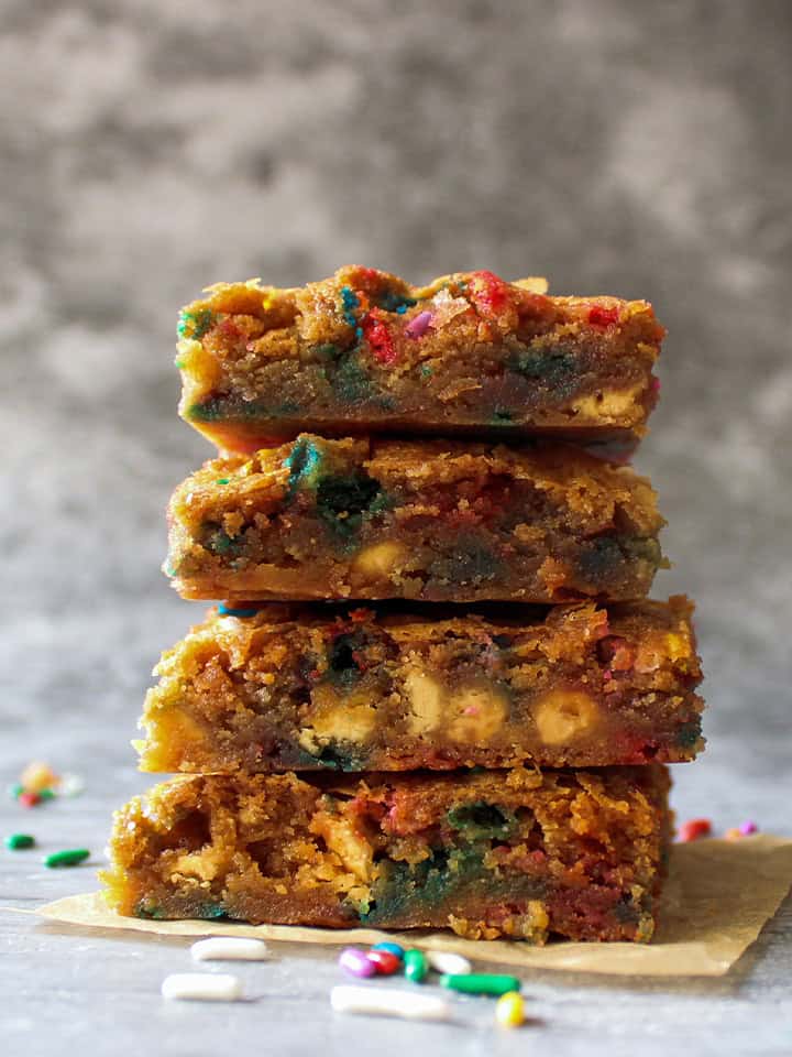 A stack of three funfetti blondies with sprinkles scattered around.