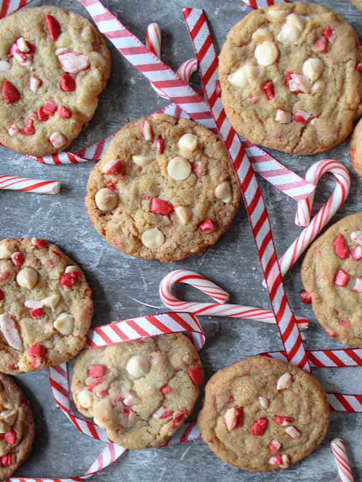 White chocolate peppermint cookies scattered around with candy canes and ribbon.